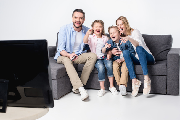 Familia sentada en un sofá y viendo televisión
 - Foto, Imagen
