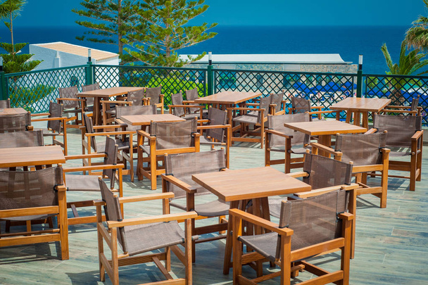 Houten tafels en stoelen in de Griekse restaurant aan zee - Foto, afbeelding