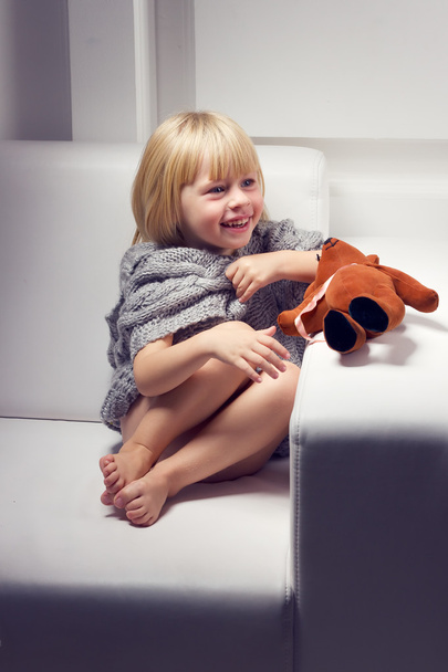 Bambina con orso sul divano
 - Foto, immagini
