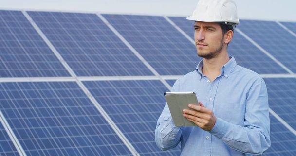 technical expert in solar energy photovoltaic panels, remote control performs routine actions for system monitoring using clean, renewable energy. concept of remote support technology - Φωτογραφία, εικόνα
