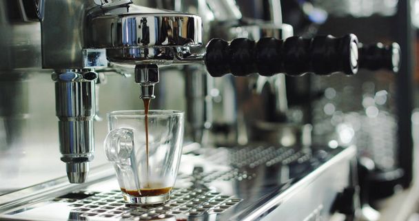 Super slow motion of hot espresso coffee pouring into a two white porcelain cups from coffee machine in 4k ( top view close up) - Fotoğraf, Görsel