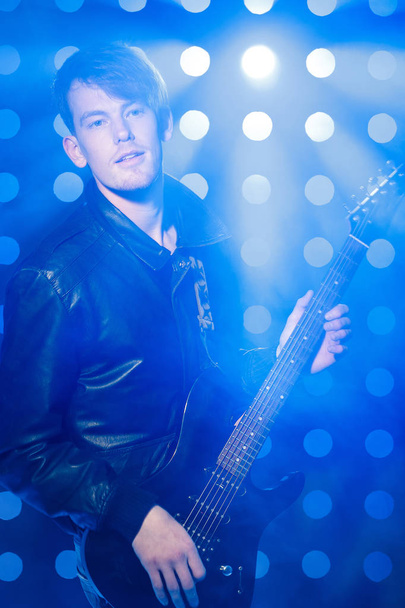 young rock musician playing electric guitar and singing. Rock star on background of spotlights - Foto, Bild