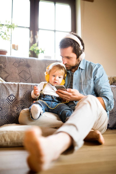 Father and son with smartphone and earphones, listening music. - Foto, immagini