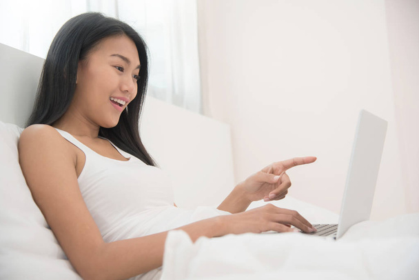 Asian girl using on laptop on her bed. - Valokuva, kuva
