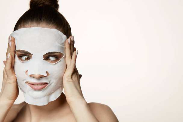 Skin Treatment. Young Woman Putting Cosmetic Mask On Facial Skin - Valokuva, kuva