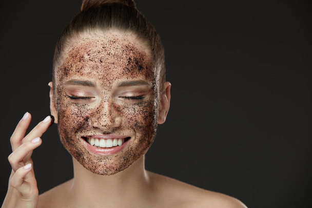 Face Skin Scrub. Smiling Girl Applying Coffee Mask Scrub On Skin - Fotó, kép