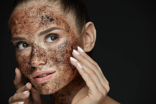 Beauty Face. Portrait Of Young Woman Putting Coffee Scrub - Foto, afbeelding