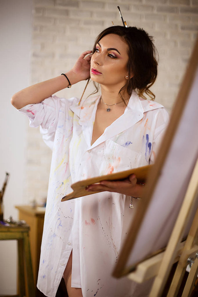 Painter girl in studio in white shirt  - Фото, зображення