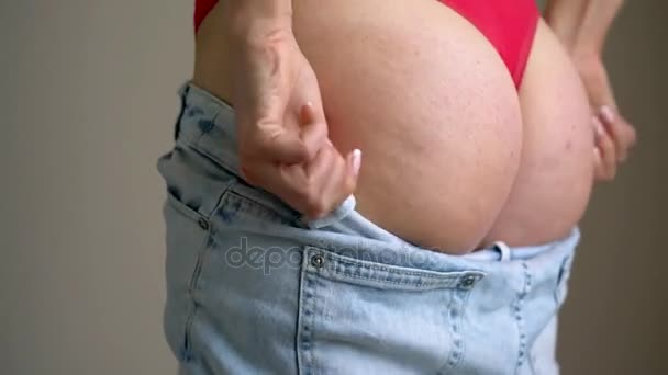 Женщина натягивает джинсы на ягодицы целлюлитом
 - Кадры, видео