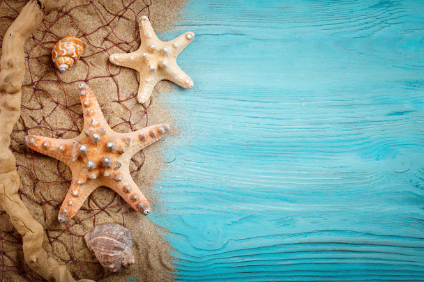 Starfish, pebbles and shells lying on a blue wooden background . There is a place for labels. - Photo, image