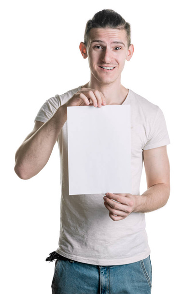 Jonge knappe man met een blanco vel papier, kijkt verbaasd schot. Plaats voor de handtekening, tekst. Verticale frame - Foto, afbeelding