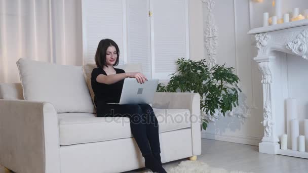 Beautiful girl relaxing on sofa using laptop and smilling - Imágenes, Vídeo