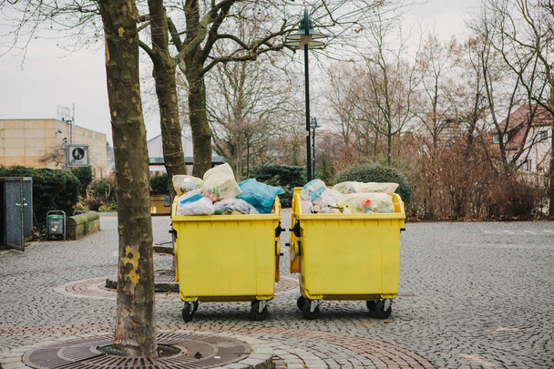 Dwie żółte pojemniki śmieci na ulicy w Niemczech. Zbieranie i unieszkodliwianie odpadów komunalnych. - Zdjęcie, obraz