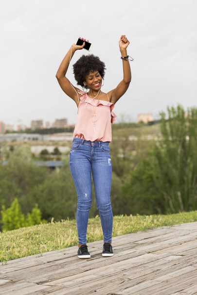 Happy young beautiful afro american woman listening to music in  - Photo, image