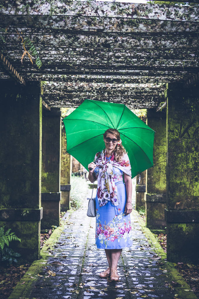 Woman with umbrella in the tropical park of Bali island, Indonesia. - Photo, Image