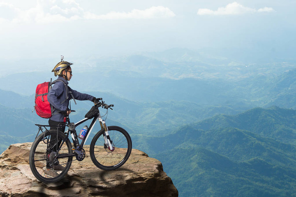 Cyclist standing with bicycle on top of hill - Photo, Image