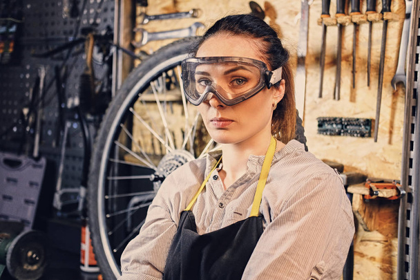 Vrouwelijke fiets monteur op gereedschap staan - Foto, afbeelding