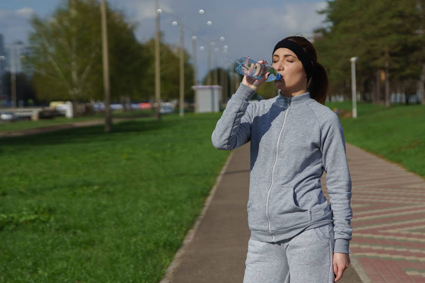 屋外の水を飲む若い女性の肖像画。スポーツ フィットネス女性ランナー ジョギングの後. - 写真・画像