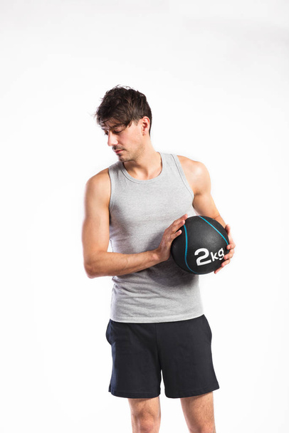 Handsome fitness man holding medicine ball, studio shot. - Photo, image