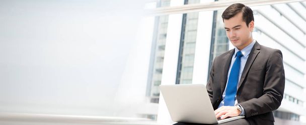 Бізнесмен, використовуючи ноутбук, сидячи на відкритому повітрі
 - Фото, зображення