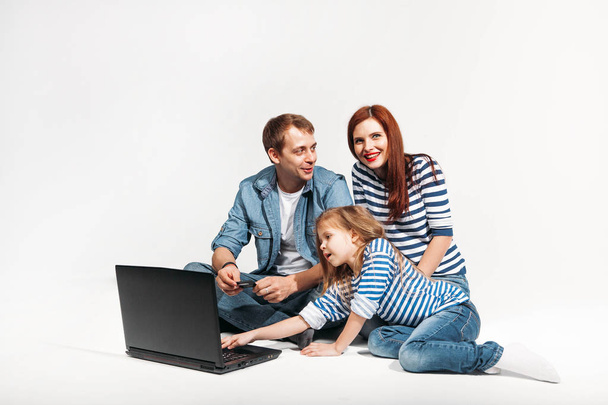 Happy family Father, mother and child lying on the floor with laptop and credit card on white background isolated - Φωτογραφία, εικόνα