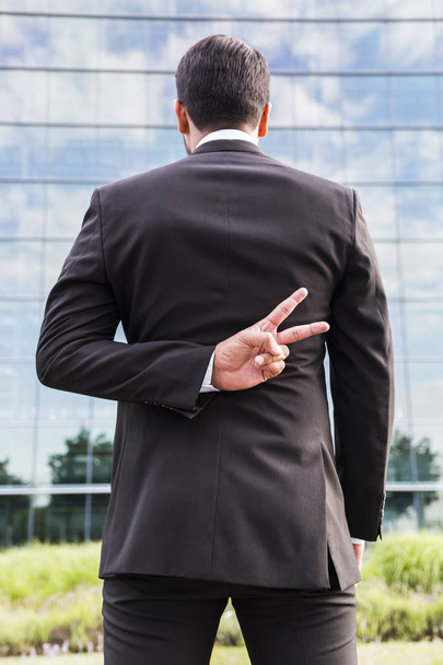Businessman or worker in suit shows peace sign near office building - Foto, Imagen