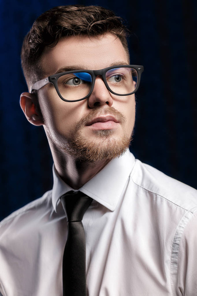 Portrait of handsome young man with glasses and white shirt on dark background - Valokuva, kuva