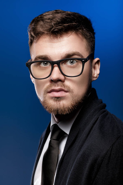 Portrait of handsome young man with glasses and white shirt on blue background - Foto, immagini