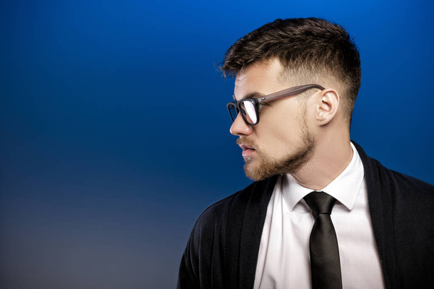 Profile of  handsome young man with glasses and white shirt on blue background - Foto, Imagem