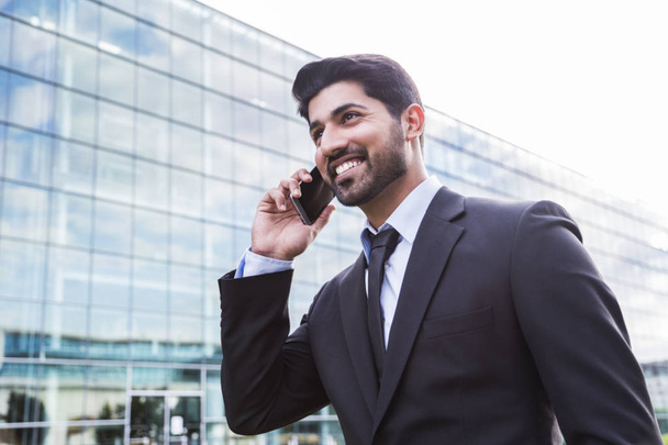 Smiling businessman or worker in suit with phone near office building - Photo, Image