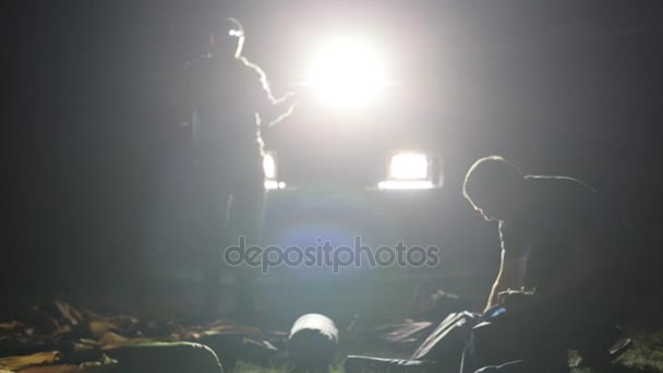 Noc strzał dwóch mans stawiajac namiot w ligh z ekspedycyjnych Suv. - Materiał filmowy, wideo