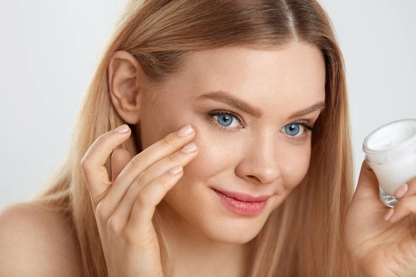 Beauty Face Care. Young Female Model Putting Cream On Eye Skin - Valokuva, kuva