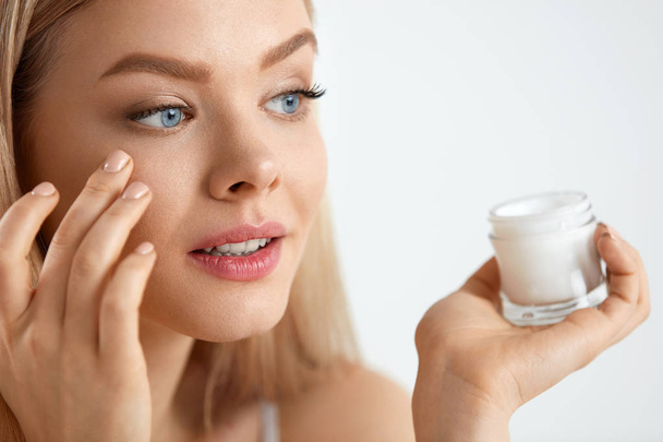 Beauty Woman Face. Girl With Fresh Skin And Cream Bottle In Hand - Foto, Imagen