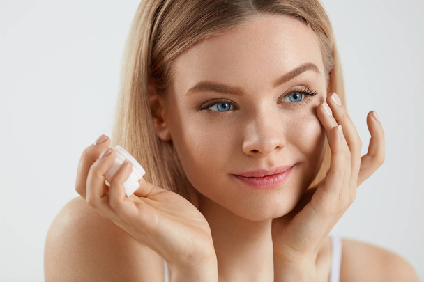 Beauty Woman Face. Girl With Fresh Skin And Cream Bottle In Hand - Foto, imagen