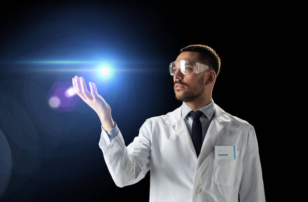 scientist in lab coat and goggles with laser light - Foto, imagen
