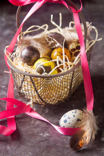Multi-colored Easter egg. Quail eggs with feathers in basket. Da - Foto, Imagen