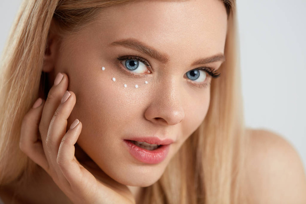 Facial Care. Woman With Drops Of Cosmetic Cream Under Eye - Фото, изображение