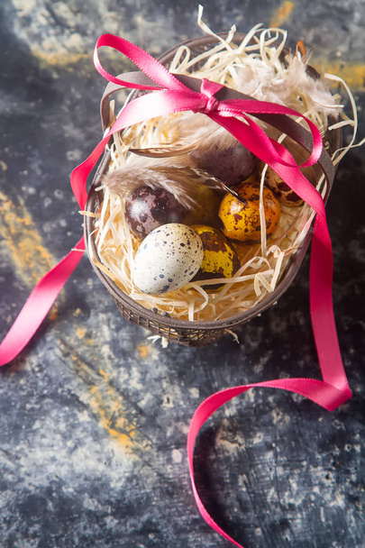 Multi-colored Easter egg. Quail eggs with feathers in basket. Da - Valokuva, kuva