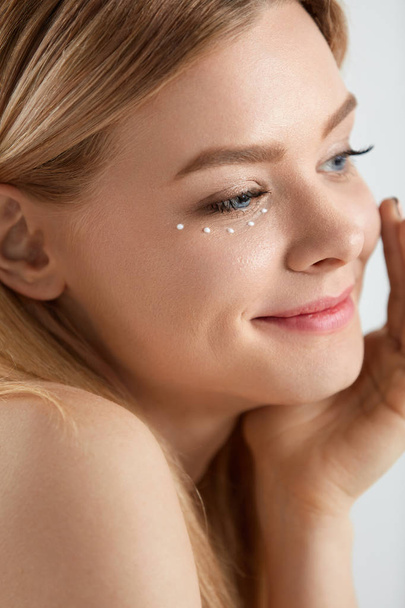 Facial Care. Woman With Drops Of Cosmetic Cream Under Eye - Valokuva, kuva