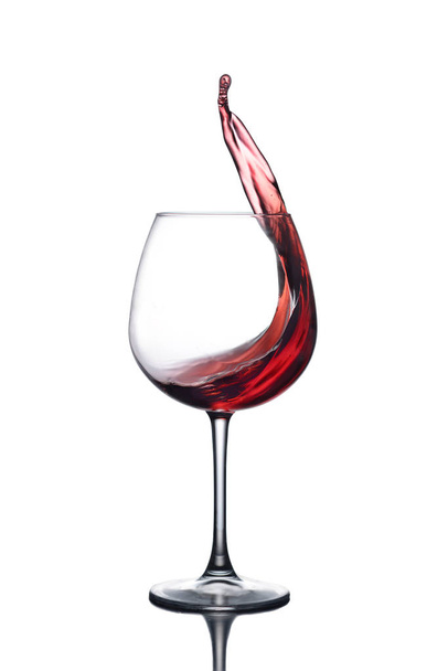 Splash of red wine in a glass on a white background with reflection - Fotoğraf, Görsel