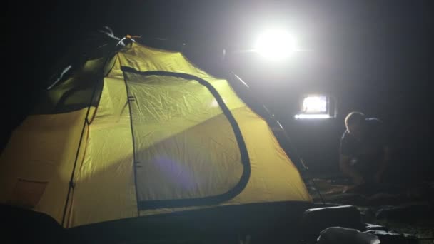 Esti felvétel két mans erecting sátor, a fény és az expedíciós Suv. - Felvétel, videó
