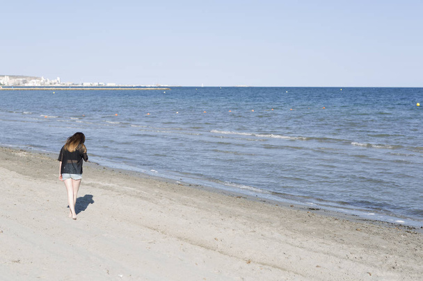 Mujer joven caminando descarte por una playa
  - Foto, imagen