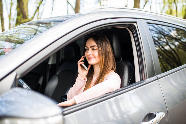 Mujer hablando por teléfono mientras conduce su coche en la calle
 - Foto, Imagen