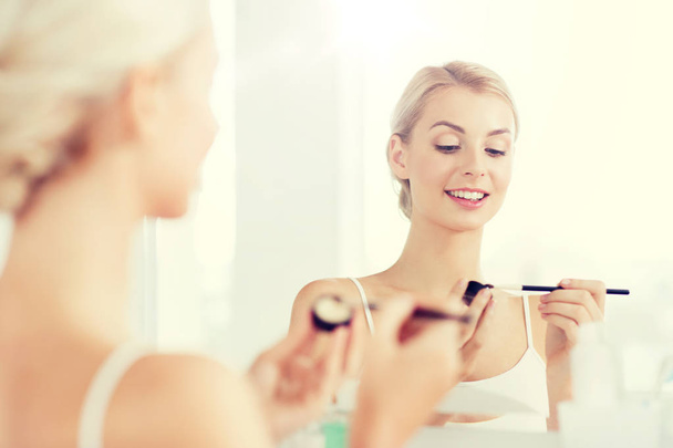 woman with makeup brush and eyeshade at bathroom - Fotoğraf, Görsel