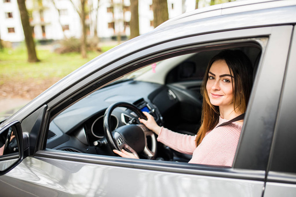 Mujer joven segura y hermosa en ropa casual mirando por encima de su hombro mientras conduce un coche
 - Foto, Imagen