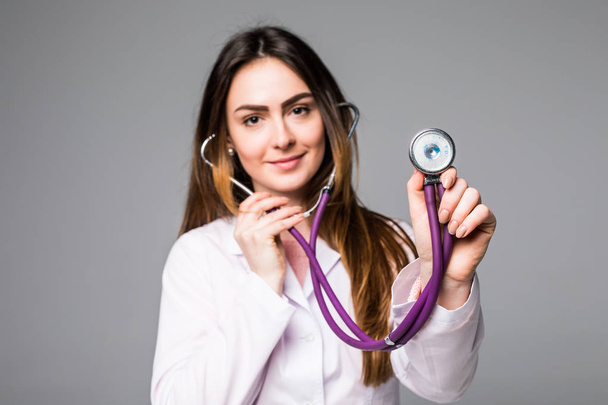 Жінка-лікар тримає стетоскоп на сірому фоні
 - Фото, зображення