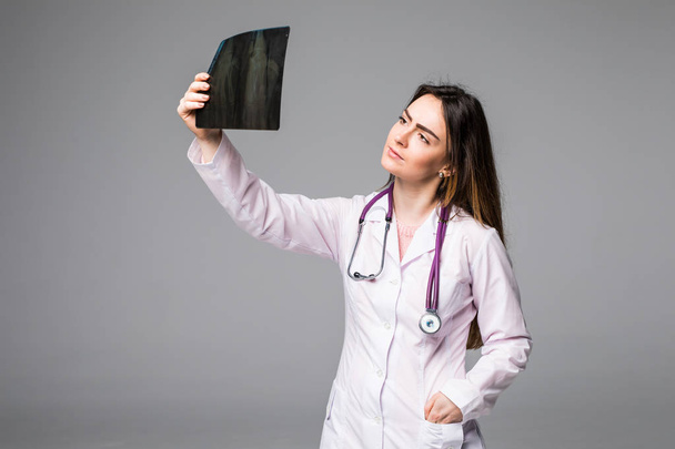 Γυναίκα γιατρός εξετάζει μια εικόνα ακτινογραφία. Εστίαση είναι στην εικόνα x-ray απομονώνονται σε γκρι φόντο. - Φωτογραφία, εικόνα