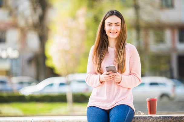 Nuori nainen puhelimen selata internetissä ja juoda kahvia kaupungin kadulla
 - Valokuva, kuva
