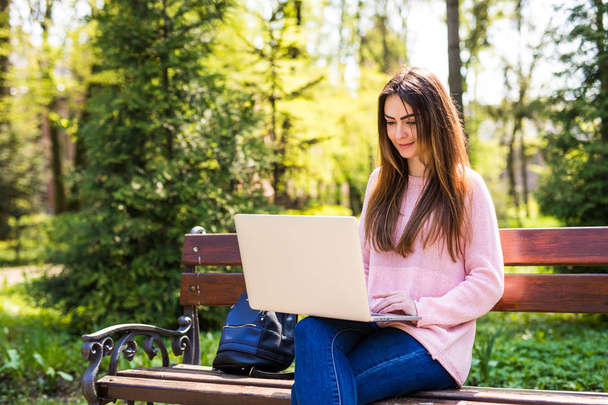 Girl using a laptop on a bench in University park - Photo, Image