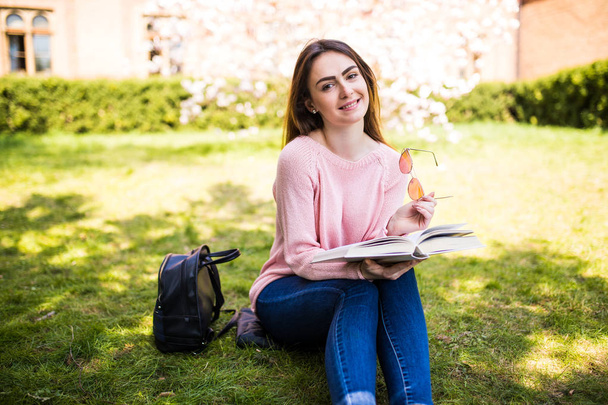 fiatal nő olvasókönyv parkban a fű napos - Fotó, kép